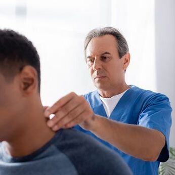 Un medico esegue un esame diagnostico su un paziente con dolore al collo.